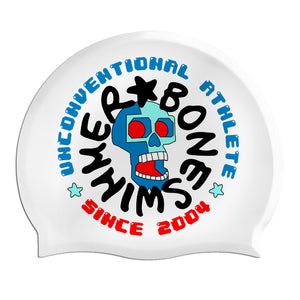 Cuffia da piscina in silicone spessorato, modello UNCONVENTIONAL  Boneswimmer con base colore bianco e grafica con un teschio in 3d e altre scritte boneswimmer style