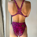 Una modella indossa il costume  Boneswimmer modello PINUP MACULATO  e mostra la parte dietro maculata nero e rosa