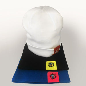 Berretto beanie in maglia, bianco con etichetta Boneswimmer a contrasto color porpora appoggiato su altri berretti in variante nera e blu