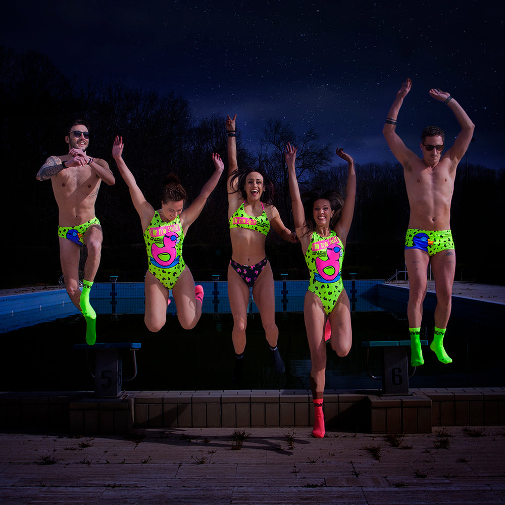 Cinque modelli saltano da un gradino indossando un costume da allenamento nuoto Boneswimmer (per le donne il PINUP 334pf), tutti con stampe di una papera con occhialini da nuoto su sfondo giallo