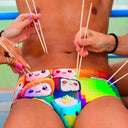 Un modello indossa il costume da nuoto Boneswimmer parigamba UCLA SUSHI con roll di sushi in stile kawaii colorati; fronte