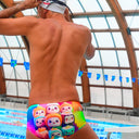 Un modello indossa il costume da nuoto Boneswimmer parigamba UCLA SUSHI con roll di sushi in stile kawaii colorati; posteriore