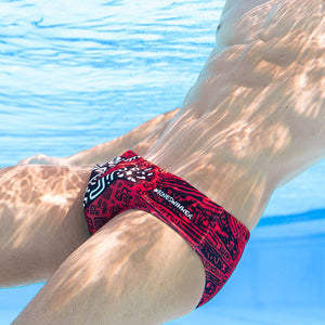 Un modello fotografato sott'acqua in piscina indossa il costume parigamba UCLA TRIBALE con un simpatico mostro in stile pop art